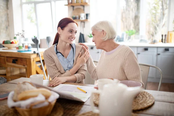 Grey-haired woman feeling thankful to caregiver — Stock Photo, Image