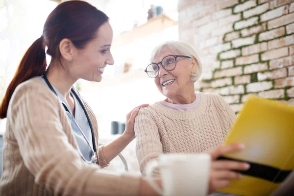 Enfermera pelirroja sonriendo mientras habla con una anciana amable —  Fotos de Stock