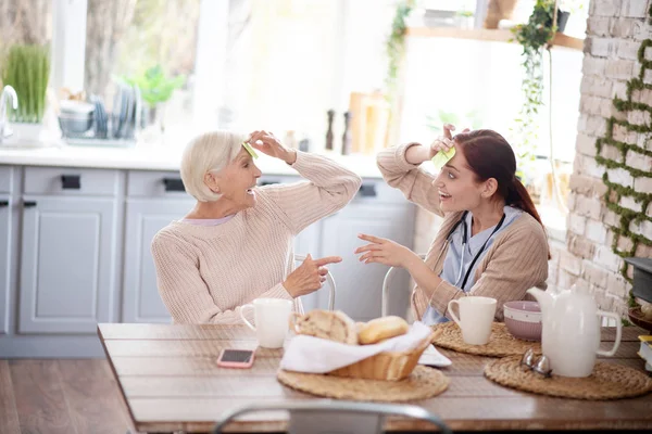 Beaming aged lady feeling happy spending time with caregiver — Stock Photo, Image