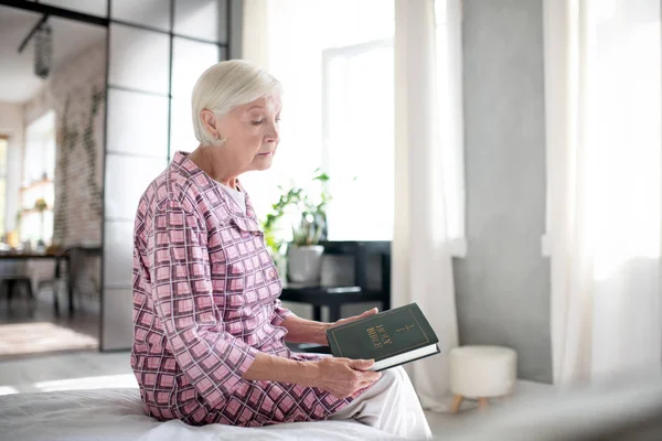 Mulher aposentada de cabelos grisalhos segurando Bíblia Sagrada — Fotografia de Stock