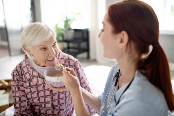 Caring nurse feeding aged woman in the morning — Stock Photo, Image
