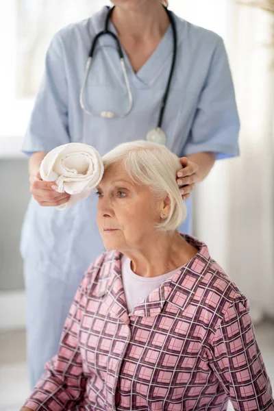 Soins infirmiers mettre serviette froide à la tête de la femme âgée — Photo