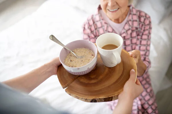 Mujer anciana sonriendo antes de comer avena y beber té — Foto de Stock