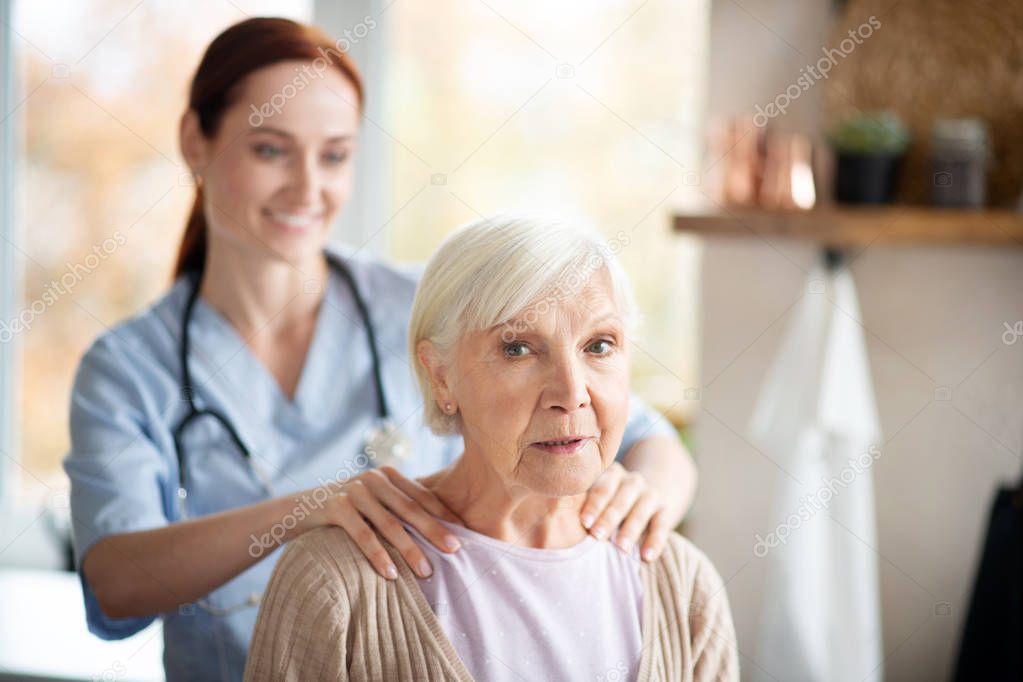 Grey-haired woman enjoying massage of shoulders