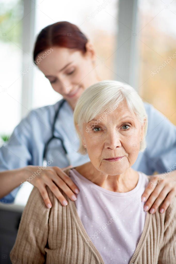 Caregiver doing massage for retired aged woman