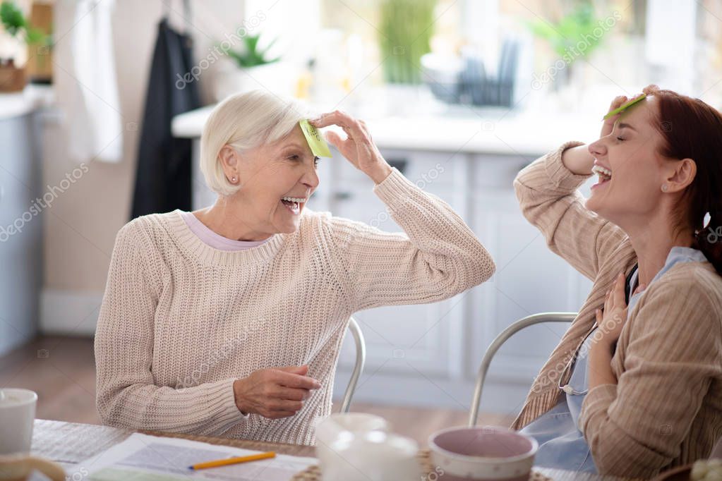 Laughing pensioner playing words game with nurse