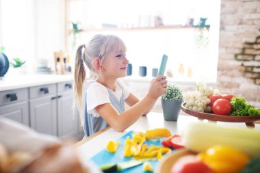 Sarışın kız babasının yanında dururken akıllı telefon kullanıyor.
