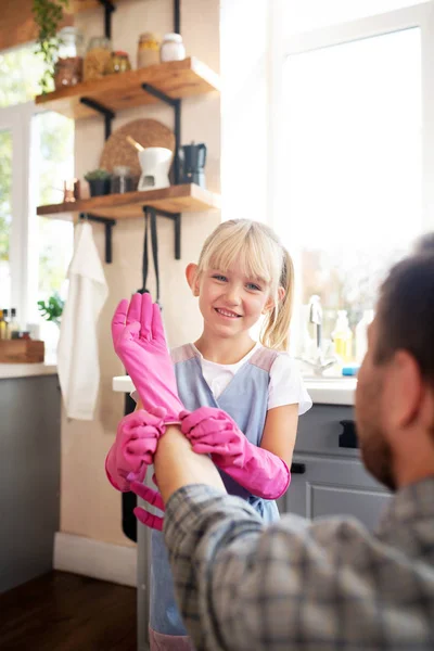 Cheerful blonde daughter helping father to put glove on — Stock Photo, Image