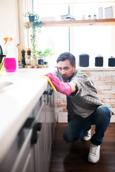 Pantolon ve beyaz spor ayakkabı giyen bir adam mutfağı temizliyor. — Stok fotoğraf
