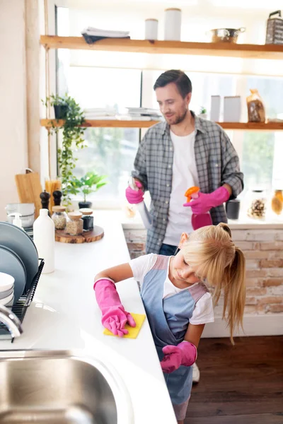 Daughter wearing gloves helping daddy to clean kitchen — Stock Photo, Image