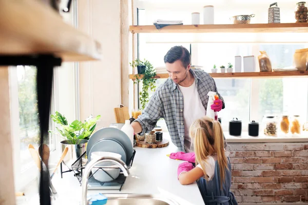 Joven moreno limpiando cocina con hija —  Fotos de Stock