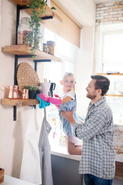 Sorridente papà sollevamento figlia mentre spolverare scaffali — Foto Stock