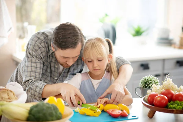 Handsome daughter assisting daughter while cutting vegetables — Stock Photo, Image