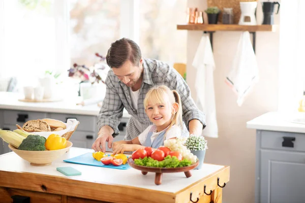 Blonde daughter smiling while cooking with father — Stock Photo, Image