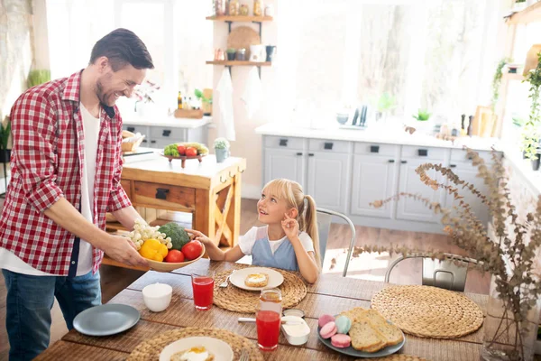 Padre riendo mientras su hija toma tomate para desayunar —  Fotos de Stock