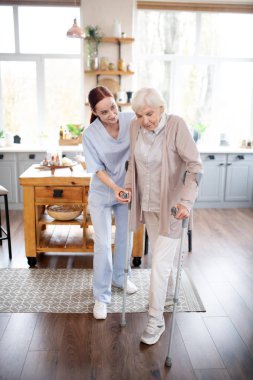 Emekli kadın ameliyattan sonra koltuk değnekleriyle adım atıyor.