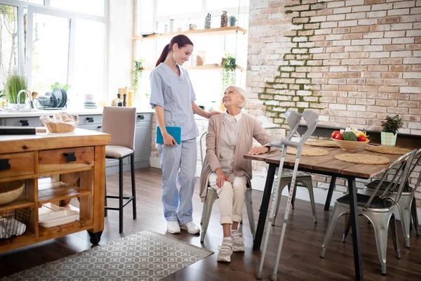 Caregiver in uniform coming to visit aged woman — Stock Photo, Image