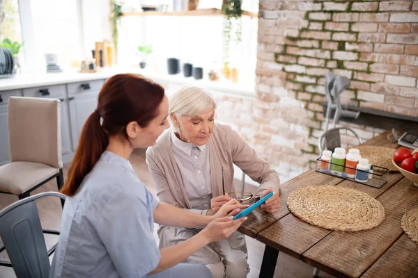 Visão superior do pensionista usando tablet com a ajuda do cuidador — Fotografia de Stock