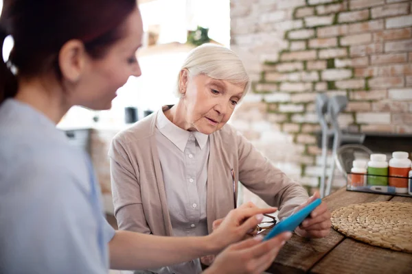 Mujer anciana que se siente involucrada en el uso de tabletas con el cuidador — Foto de Stock