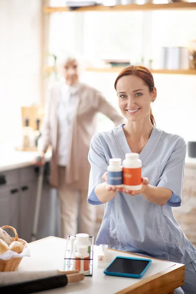 Enfermera sonriente sosteniendo dos paquetes de vitaminas — Foto de Stock
