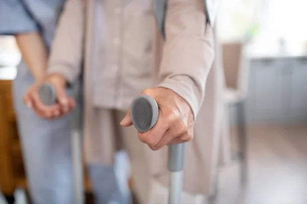 Nahaufnahme einer Rentnerin mit Krücken beim Gehen — Stockfoto