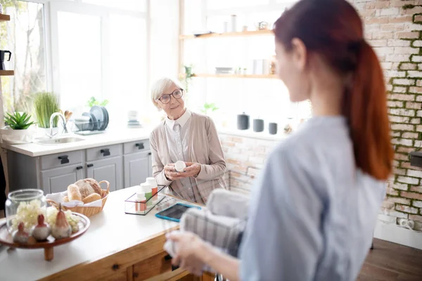 Mujer jubilada con gafas hablando con su cuidador — Foto de Stock