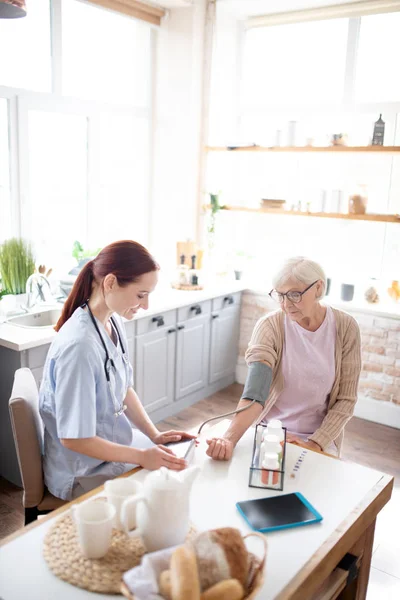 Top view of nurse measuring pressure for pensioner