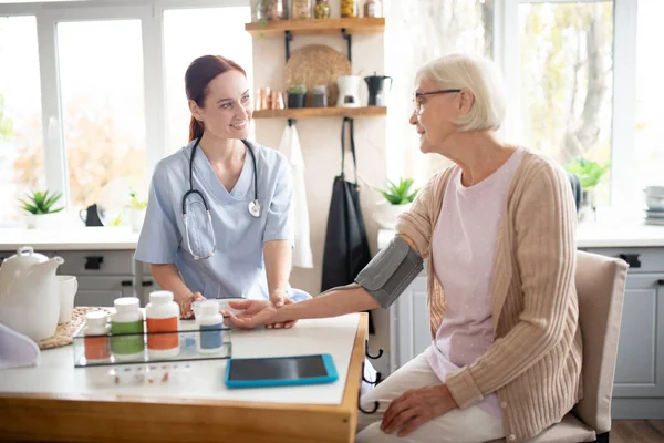 Pensionista con gafas hablando con enfermera — Foto de Stock