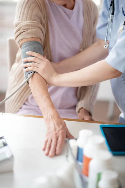 Trabajador médico que mide la presión arterial de la mujer — Foto de Stock