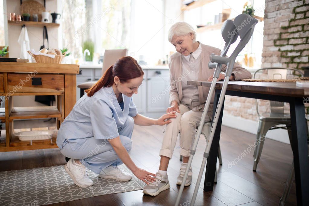 Nurse wearing uniform taking care of aged woman