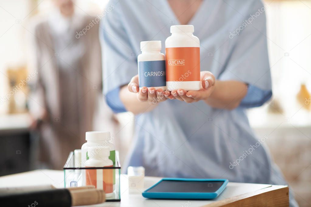 Close up of medical attendant holding packs of vitamins