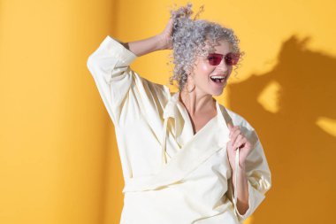 Kendine güvenen bir kadın saçına dokunuyor.