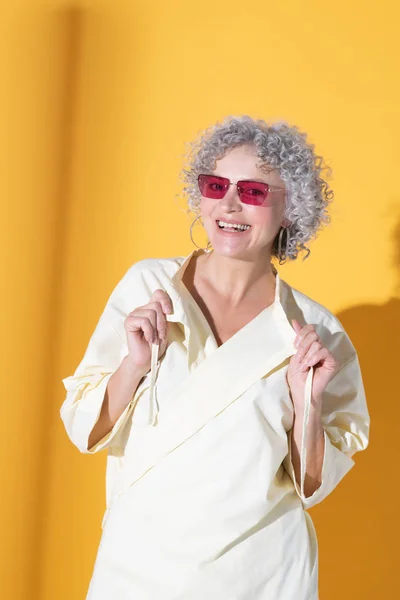 Mulher encaracolada usando óculos rosa sorrindo amplamente — Fotografia de Stock