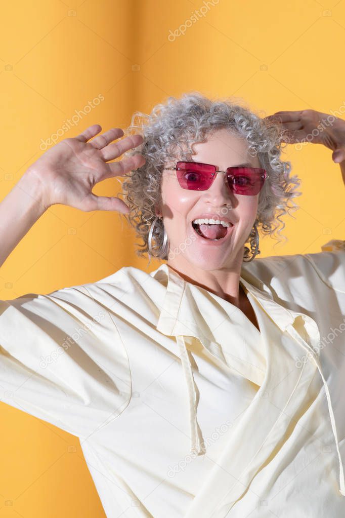Curly -haired pretty woman wearing bright sunglasses laughing