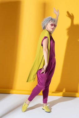 Arka planda duran pembe elbiseli ve gözlüklü kadın.