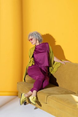 Kanepede oturan parlak elbiseli kıvırcık kadın.