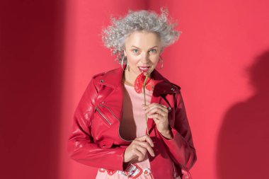 Güzel olgun bir kadın kucağında küçük kırmızı bir çiçek tutuyor