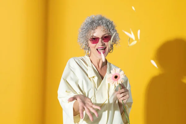 Laughing positive woman throwing petals into air