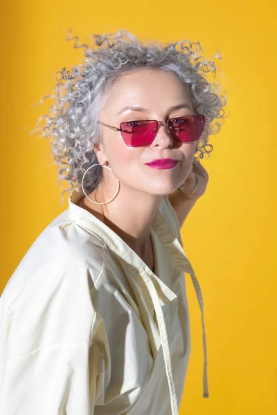 Pretty woman wearing earrings posing near background — Stock Photo, Image