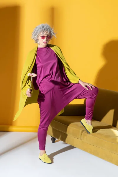 Stylish woman wearing pink clothing standing near sofa — Stock Photo, Image