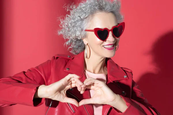 Woman in red sunglasses and jacket smiling broadly — Stock Photo, Image