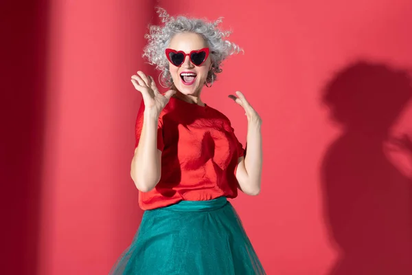 Strålande kvinna klädd i röda hjärtformade glasögon skrattar — Stockfoto