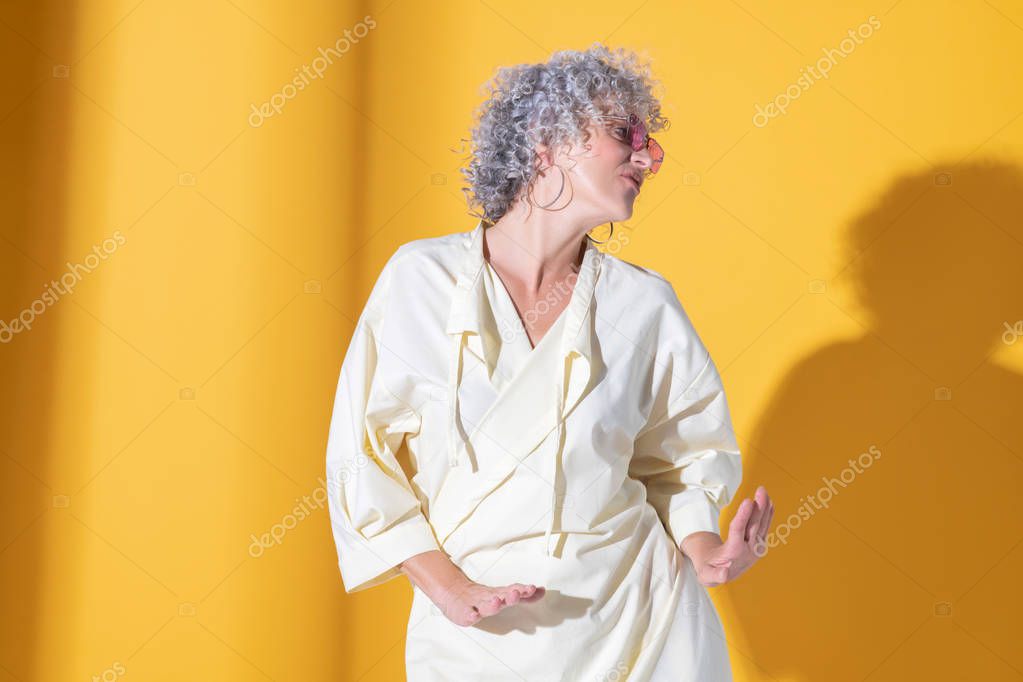Curly grey-haired woman dancing while feeling amazing