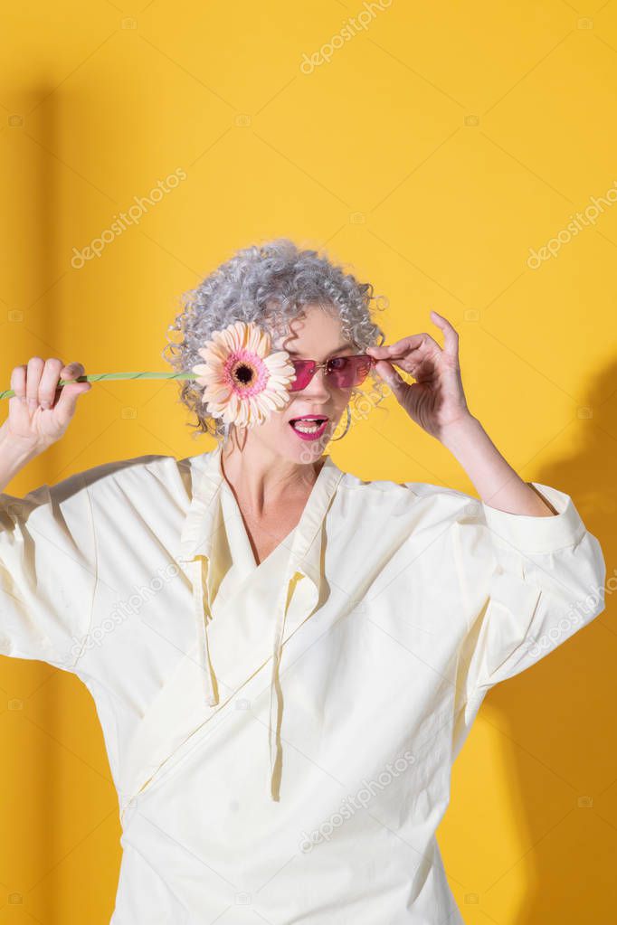 Woman wearing bright glasses holding pink flower