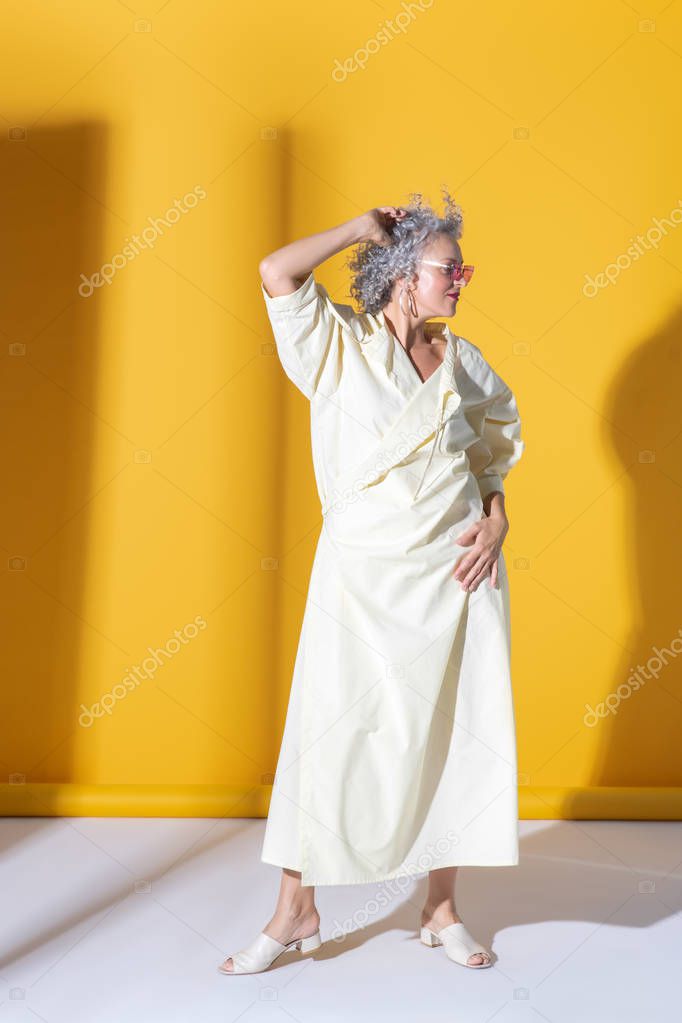 Fashionable woman wearing long white dress posing