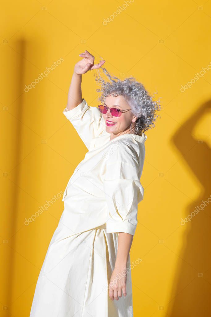 Woman wearing long dress posing near background