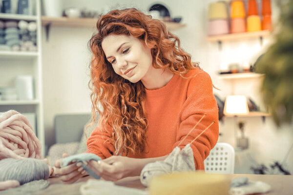 Cute long-haired girl looking at knitted sample