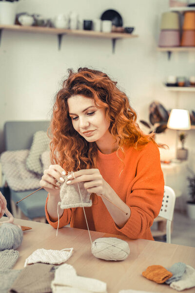 Beautiful young female knitting scarf for little client