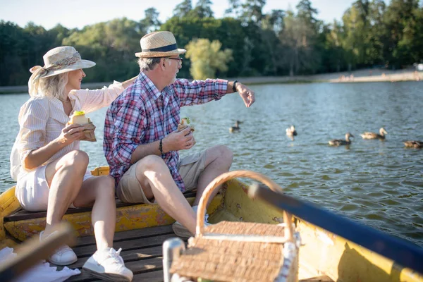 Couple sitting on boat feeding ducks and enjoying the atmosphere