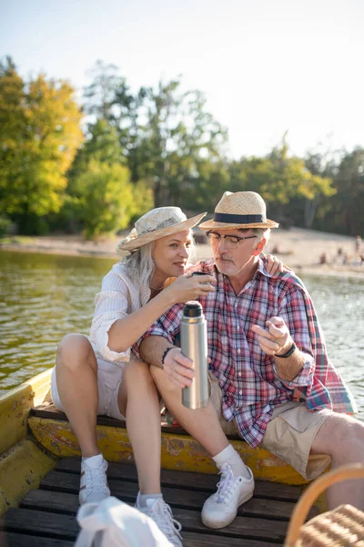 Pareja bebiendo té caliente mientras tiene increíble paseo en barco —  Fotos de Stock